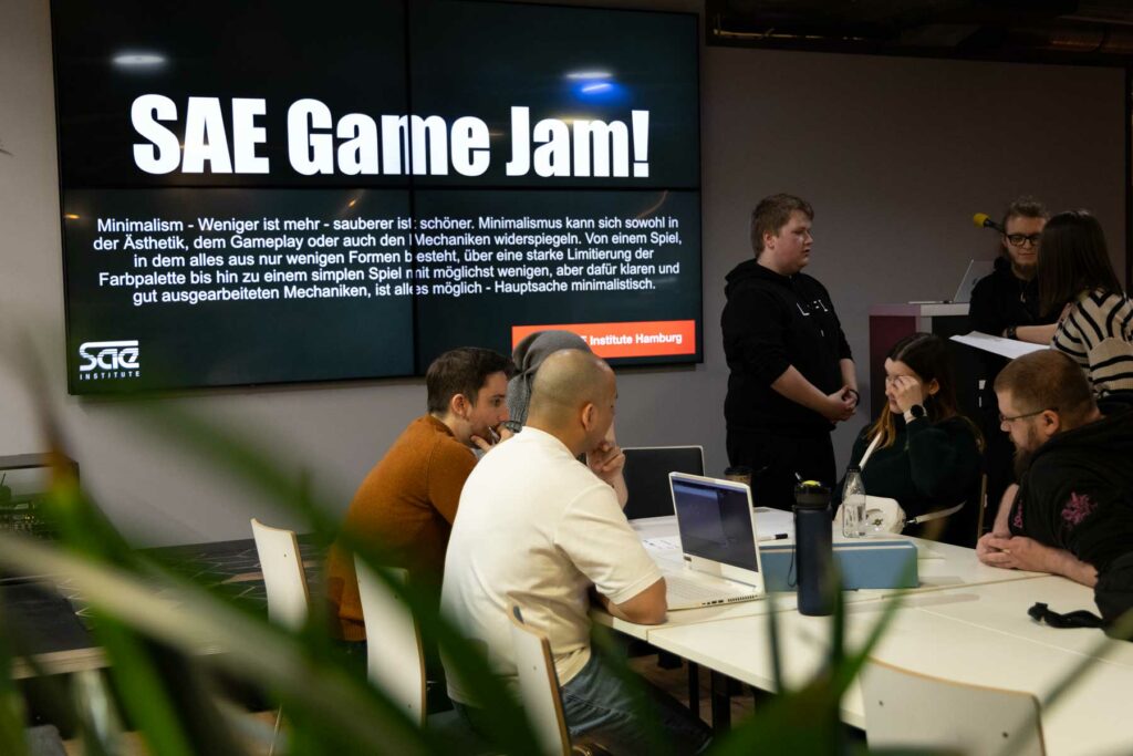 Menschen stehen gemeinsam vor Leinwand und unterhalten sich.