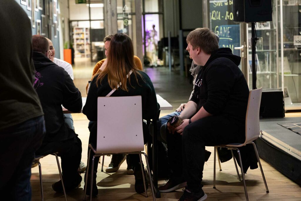 Menschen sitzen zusammen am Tisch und unterhalten sich